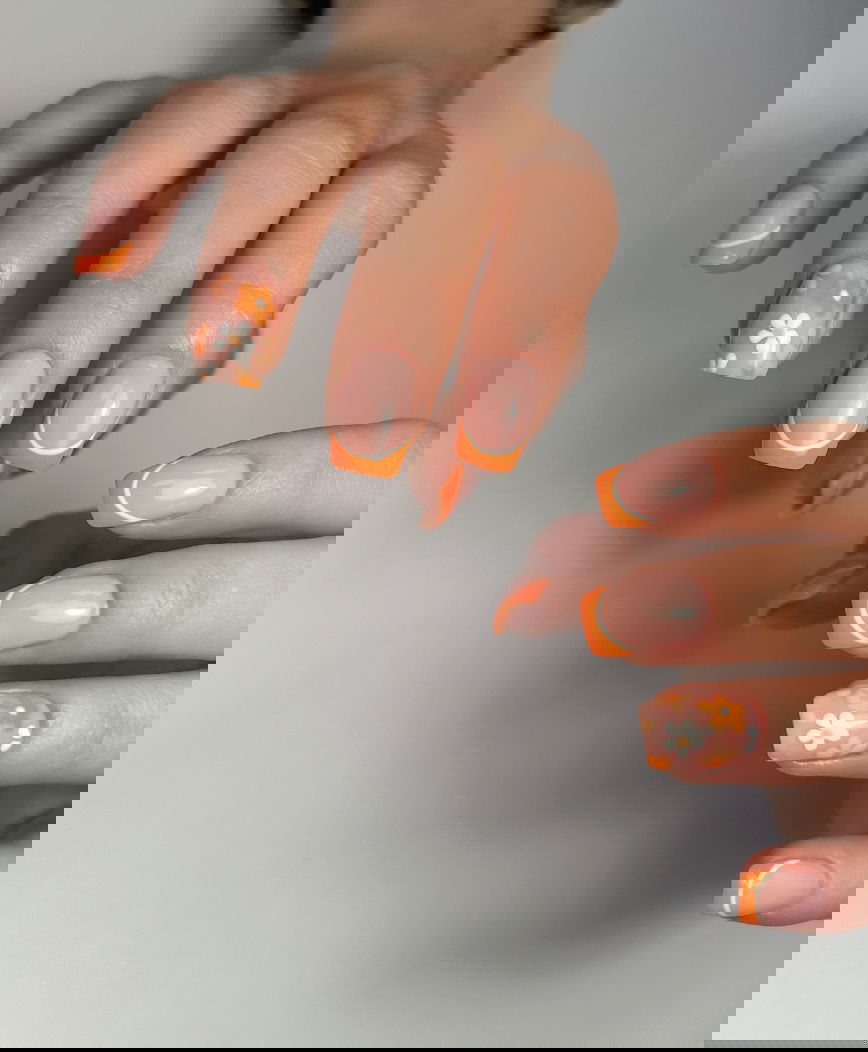Orange French tip nails with flowers