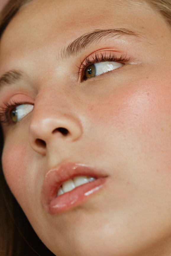 Close-up of a young woman's face with green eyes, soft make-up and beautiful skin looking to the side