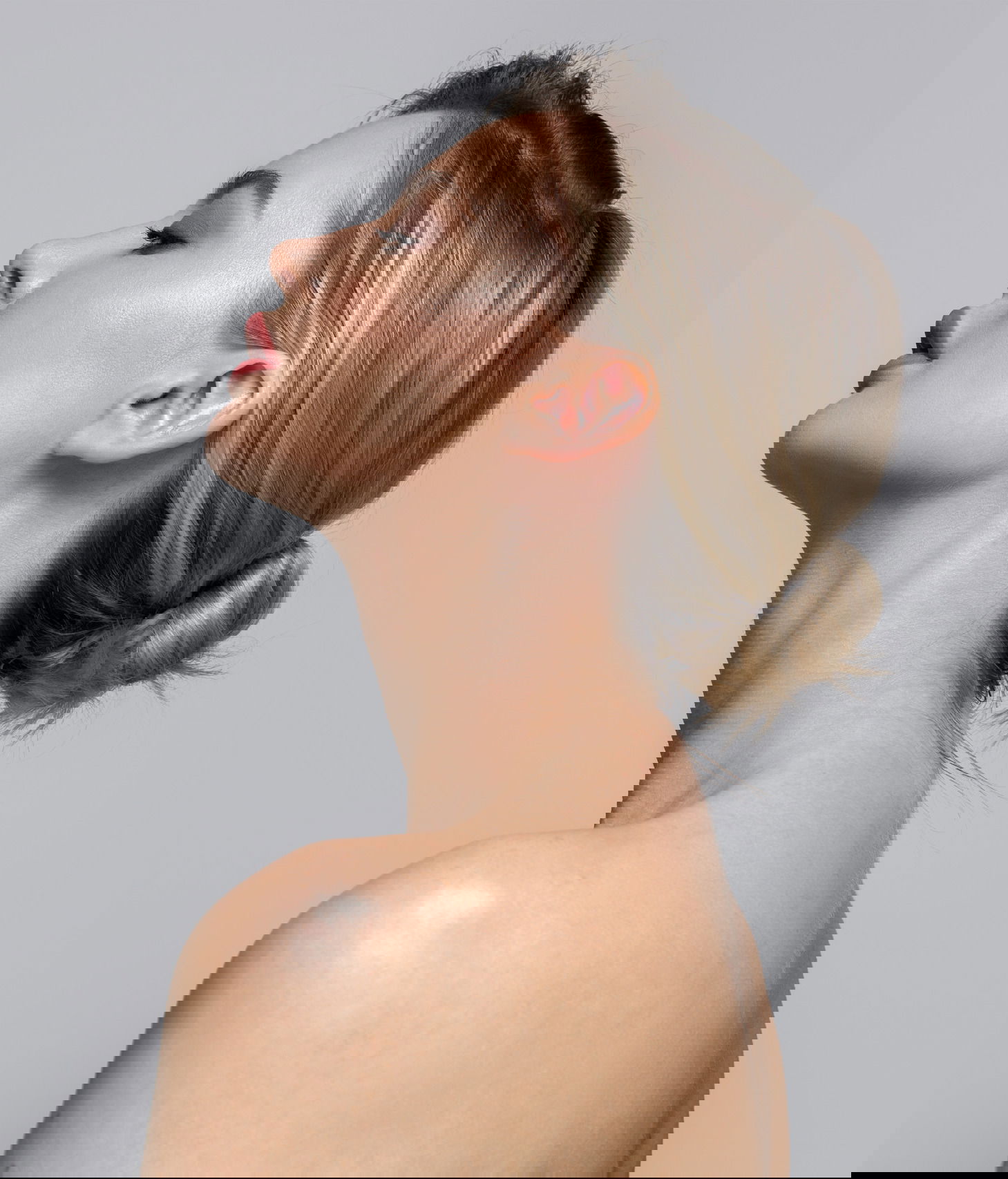 Young beautiful woman stands on her side with bare shoulders and back. Concept of hair and makeup, skin and body care face botox