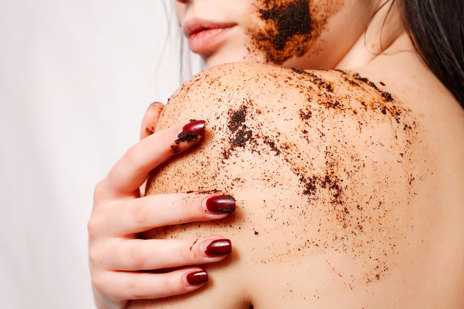 Brunette woman cleans the skin of the body coffee scrub | Live That Glow