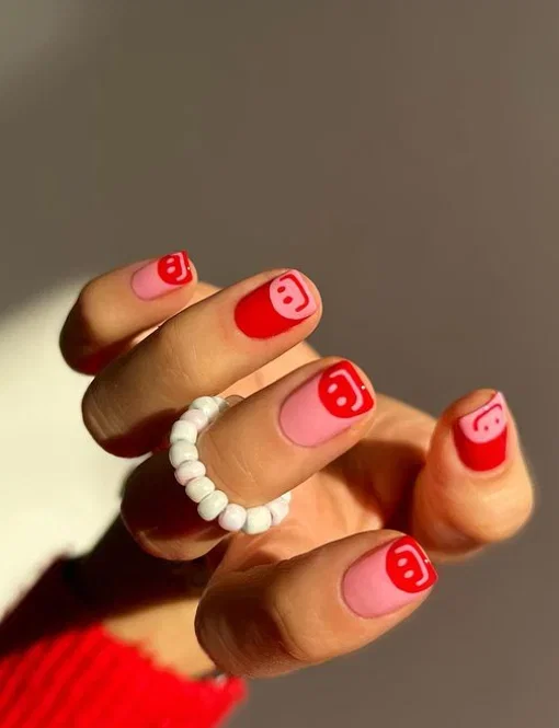 Square red and pink nails with smiley faces