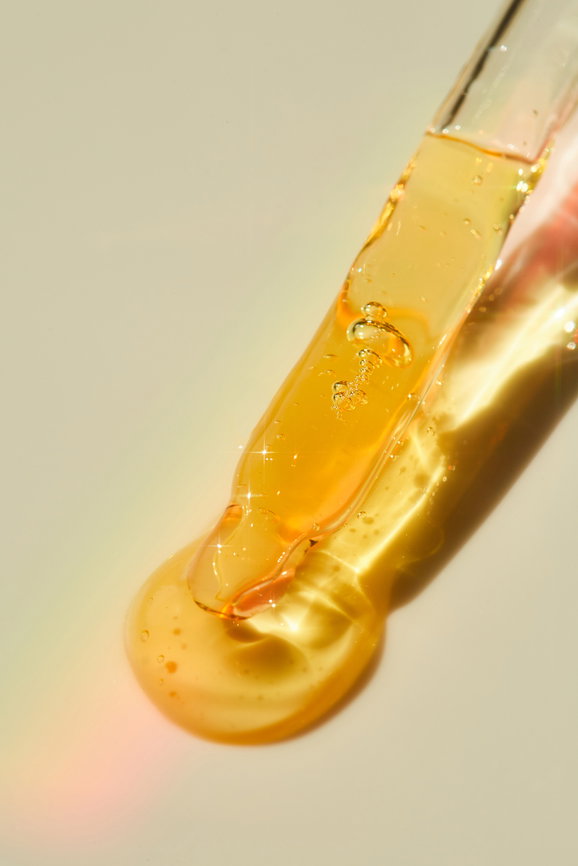 Dropper with beauty product for skincare routine over neutral background.