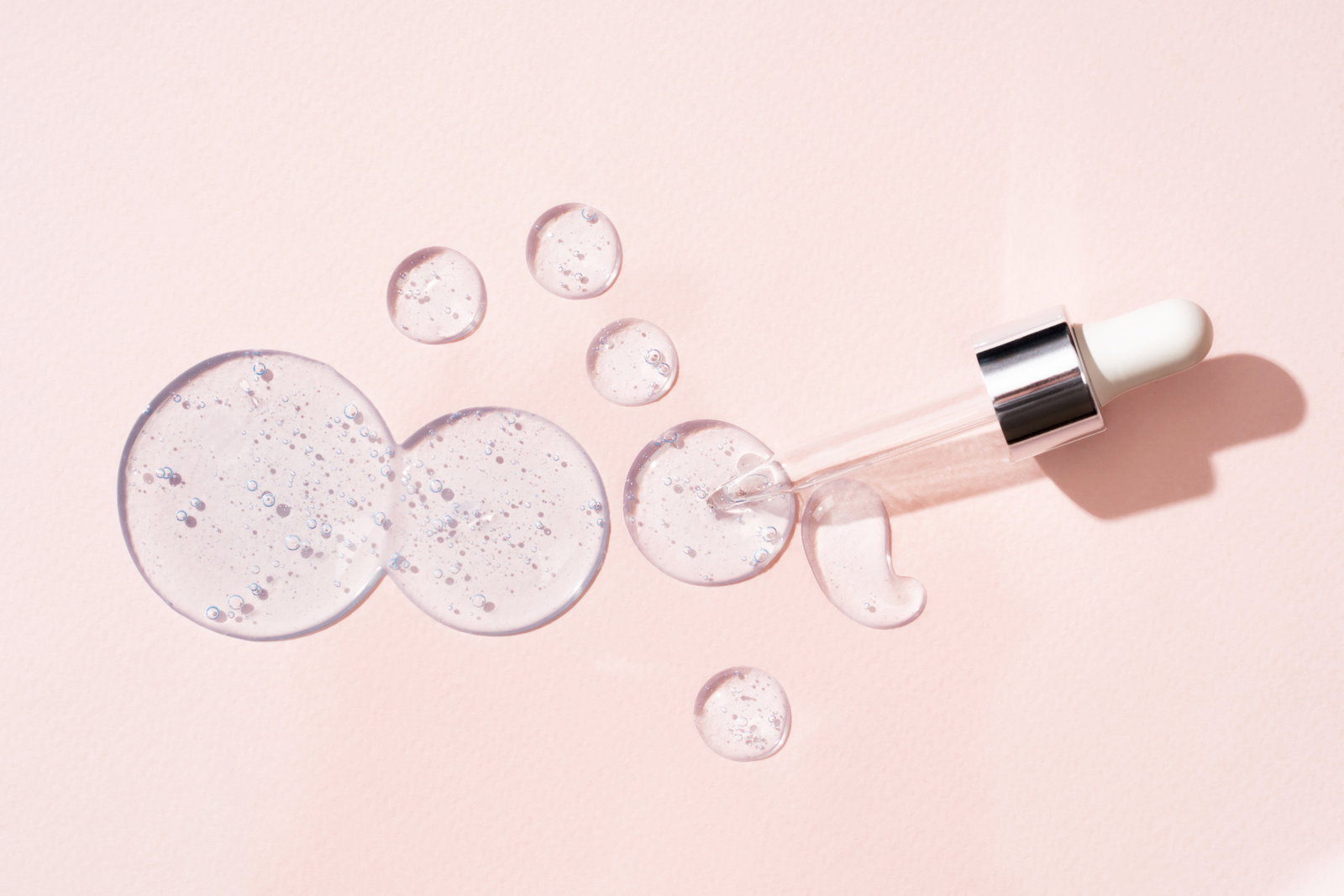 Drops and smears of cosmetics Drops of liquid transparent gel with bubbles on a beige background | Live That Glow