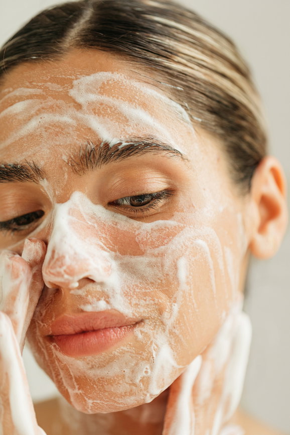 Close up of beautiful young woman washing her face with soap foam | Live That Glow
