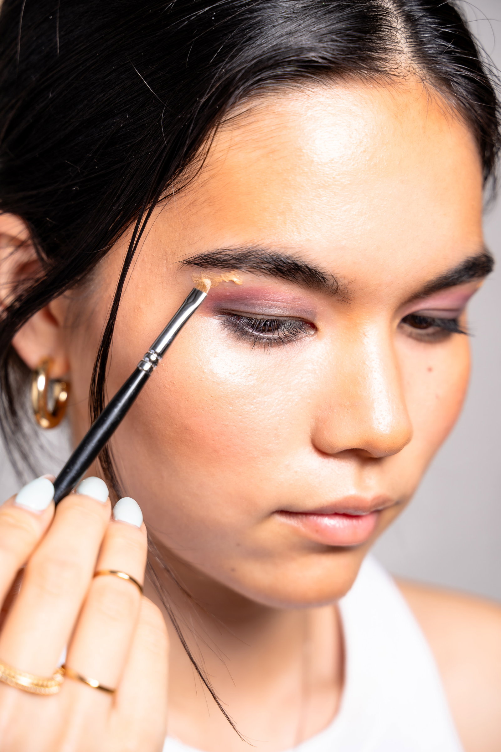 Girl showing how to apply highlighter to her brow bone as part of a smokey eye look