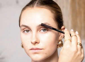 Girl applying makeup to eyebrows