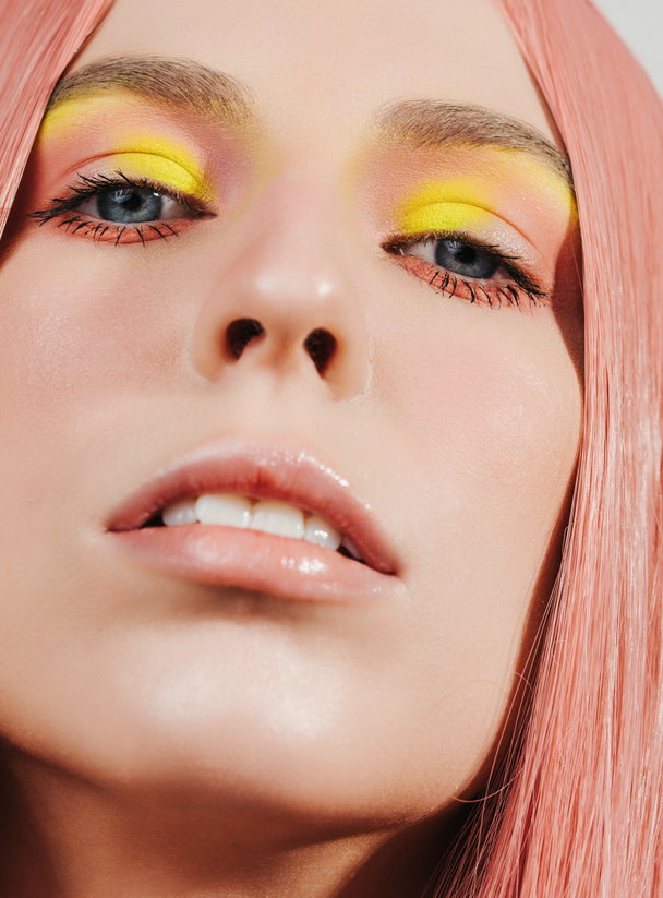 blue eyes eyeshdows Closeup beauty portrait of woman with pink and yellow eye shadows looking at camera