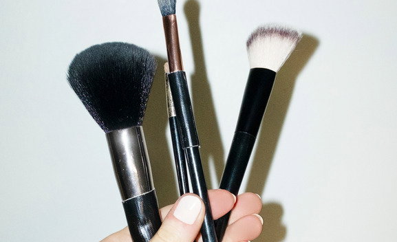 Hand holding make-up beauty cosmetics brushes and hard direct flashlight