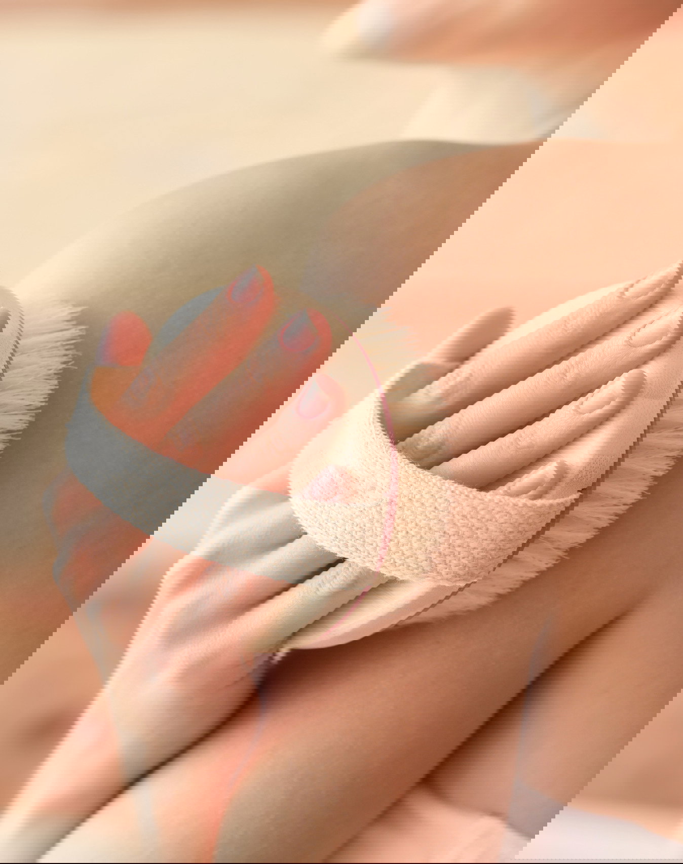 Beautiful young woman with massage brush on wooden background, closeup