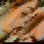 Portrait of young woman with red hair surrounded by tree leaves summer autumn tan