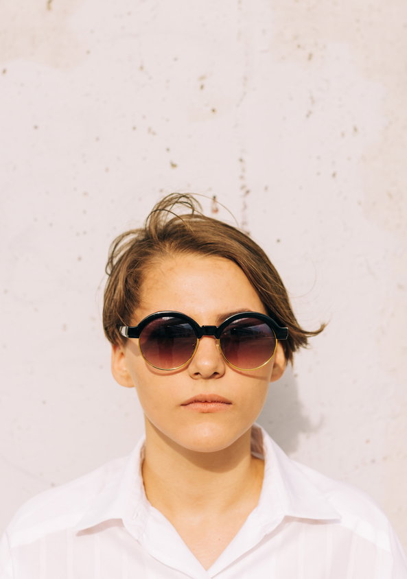 portrait of young woman with short hair and round sunglasses | Live That Glow