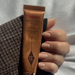 Beauty journalist wearing Charlotte Tilbury's Beauty Light Wand held in a hand