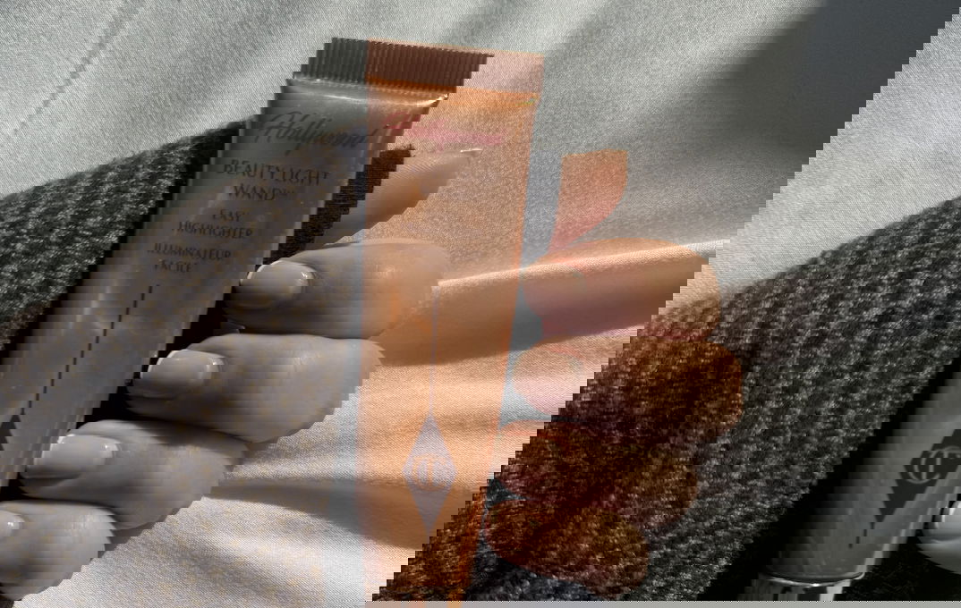 Beauty journalist wearing Charlotte Tilbury's Beauty Light Wand held in a hand