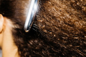 A talented young hairstylist expertly combs and styles curly hair after a haircut, leaving a satisfied customer beaming with delight in a stylish hairdressing salon | Live That Glow