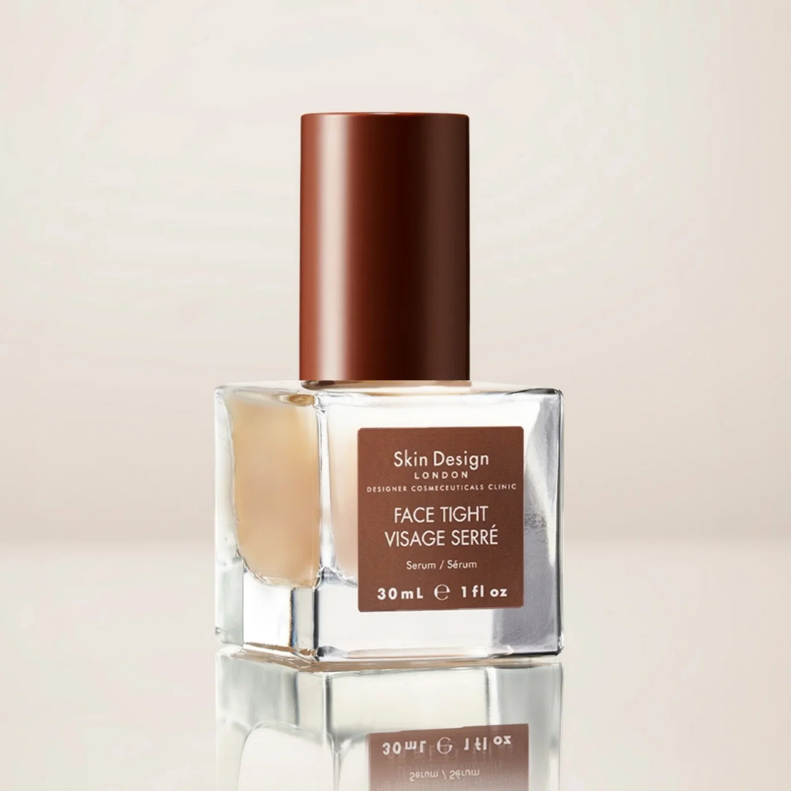 Close-up of a glass perfume bottle with a tall brown cap and a brown label reading Skin Design London Face Tight Serum, 30 mL.