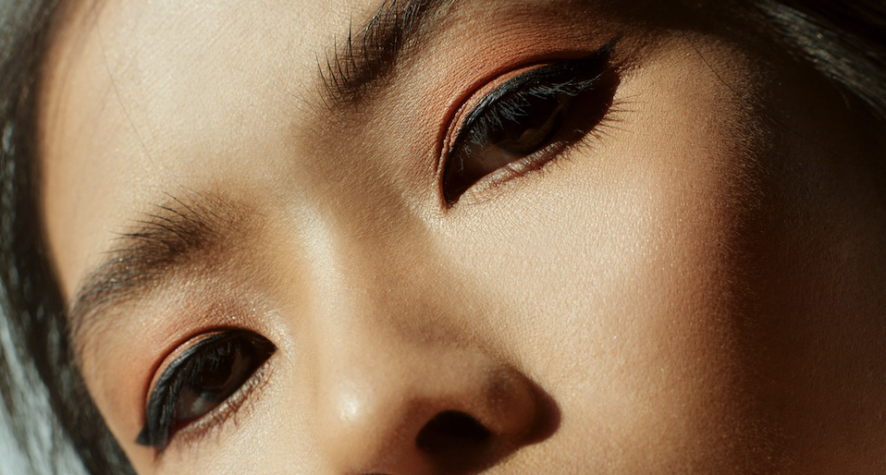 Close-up of a person’s face showing bold winged eyeliner and warm peach eyeshadow.