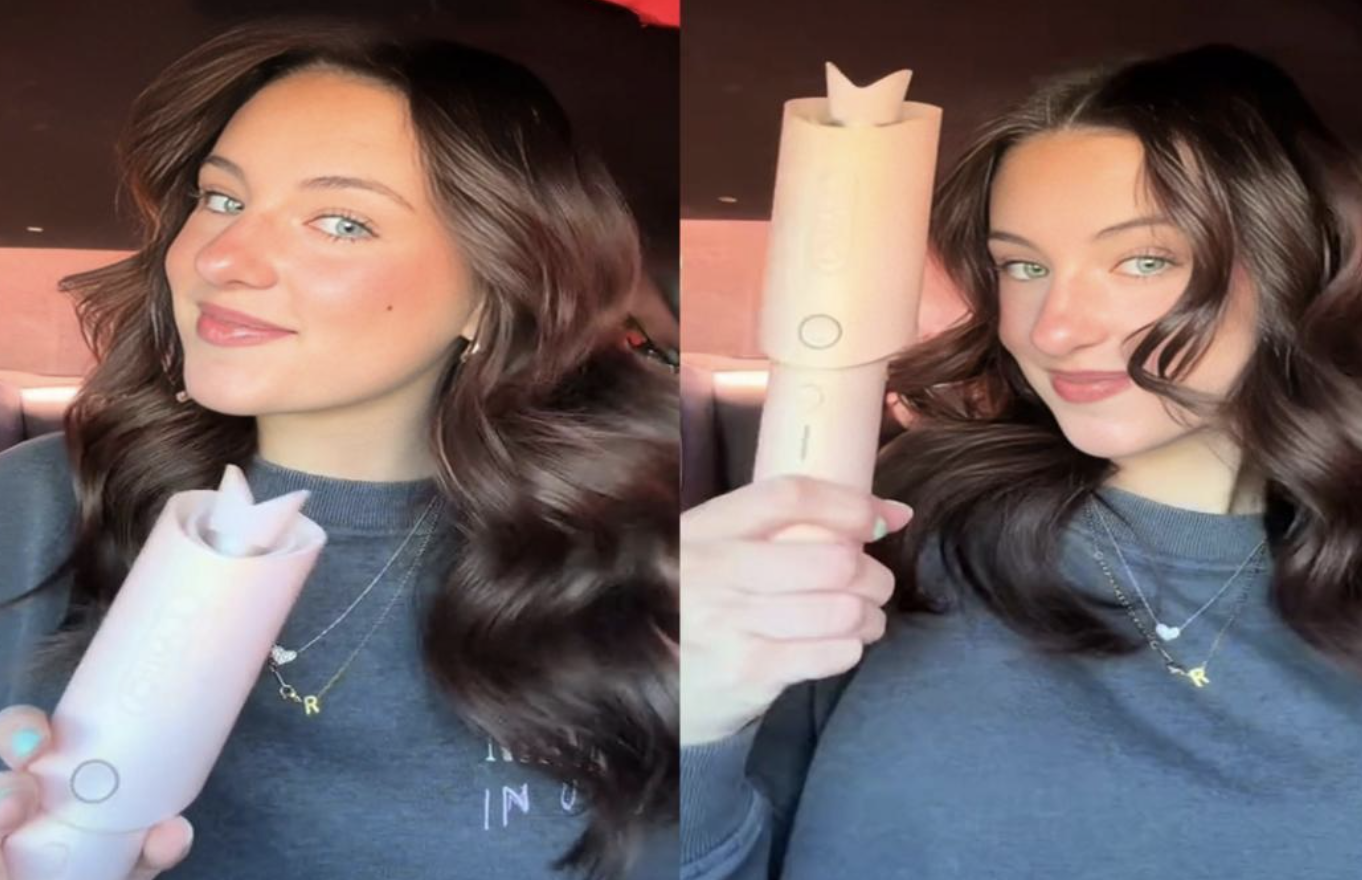 Woman in a car smiles while holding a pale pink skincare bottle toward the camera, showcasing the product.