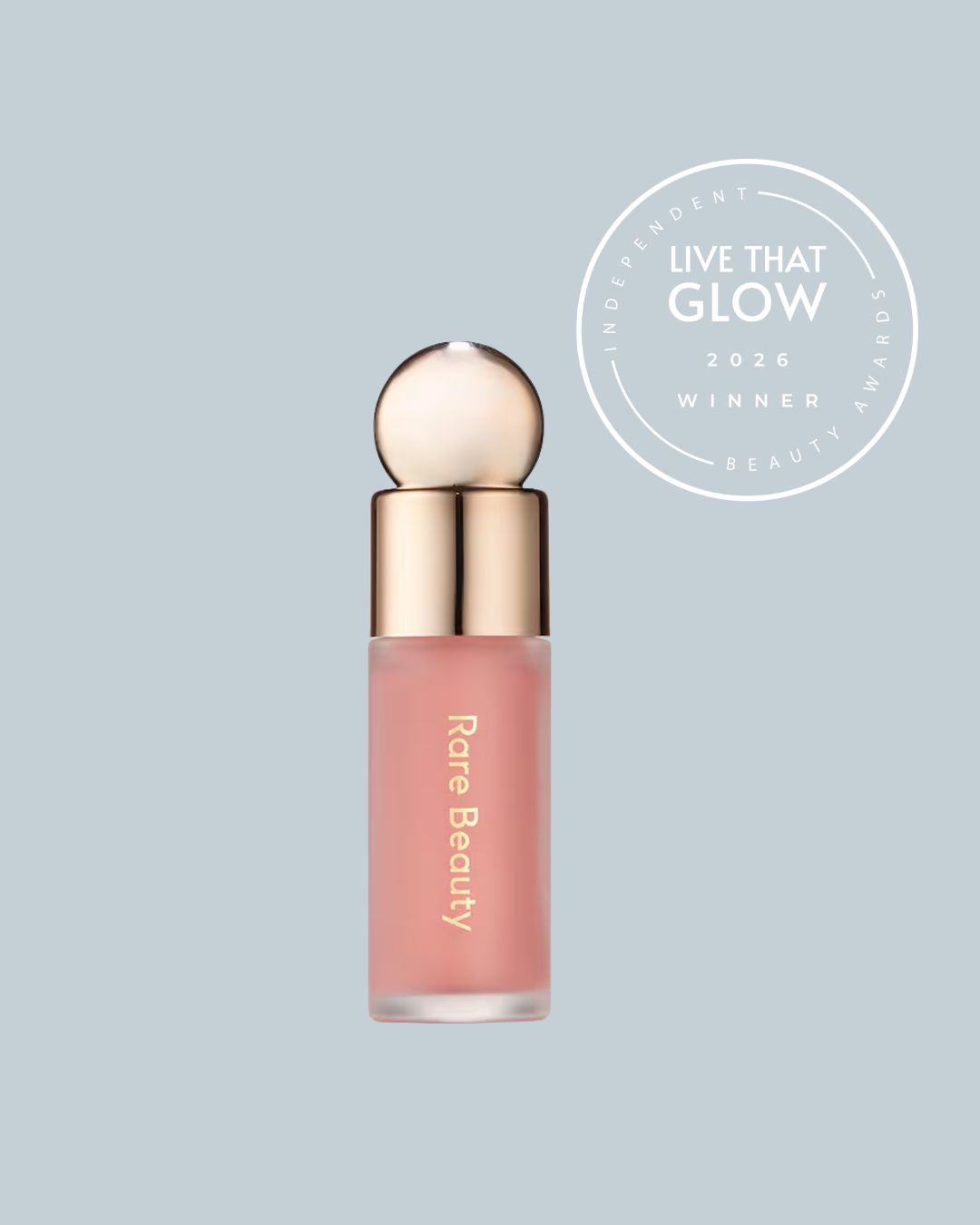 Live That Glow Independent Beauty Awards 2026 Best Accessible Beauty Product awards winner - Rare Beauty Liquid Blush | Live That Glow Rare Beauty lip gloss bottle with pink liquid and rose-gold cap on a pale blue backdrop, plus a circular 'Live That Glow 2026 Winner' badge nearby.