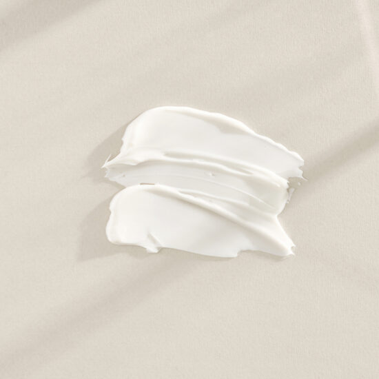 A smear of white cream spread on a pale beige surface or fabric area.