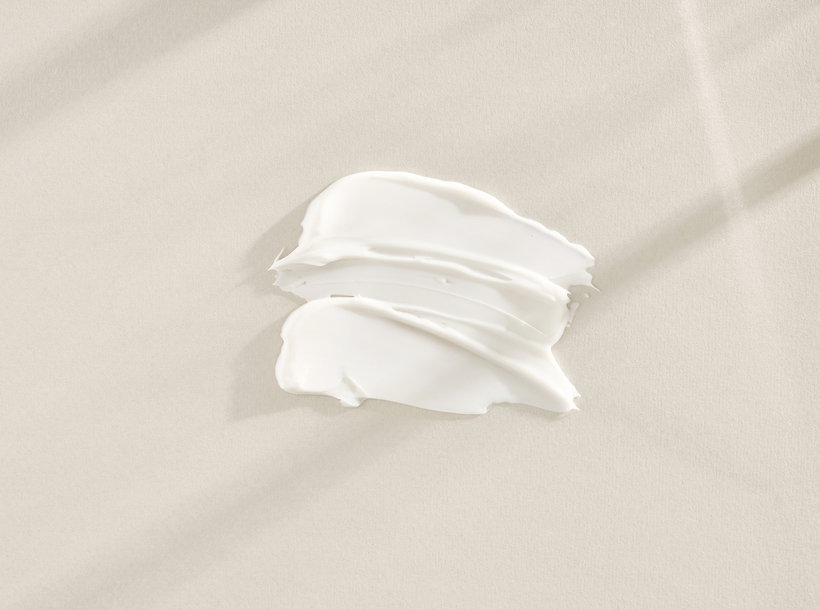 A smear of white cream spread on a pale beige surface or fabric area.