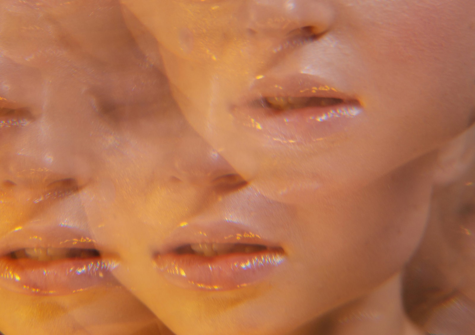 Abstract collage of peach?toned, close?up lips and facial features repeated across the frame in a warm, blurry pattern.