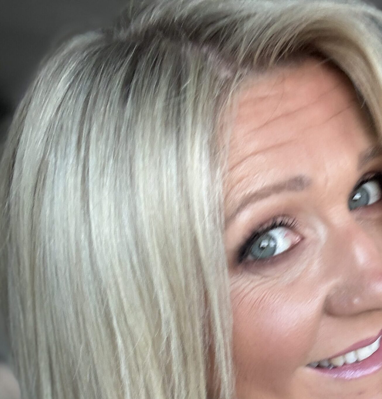 Smiling woman with long blonde hair showing results of Color Wow Money Mist in her hair