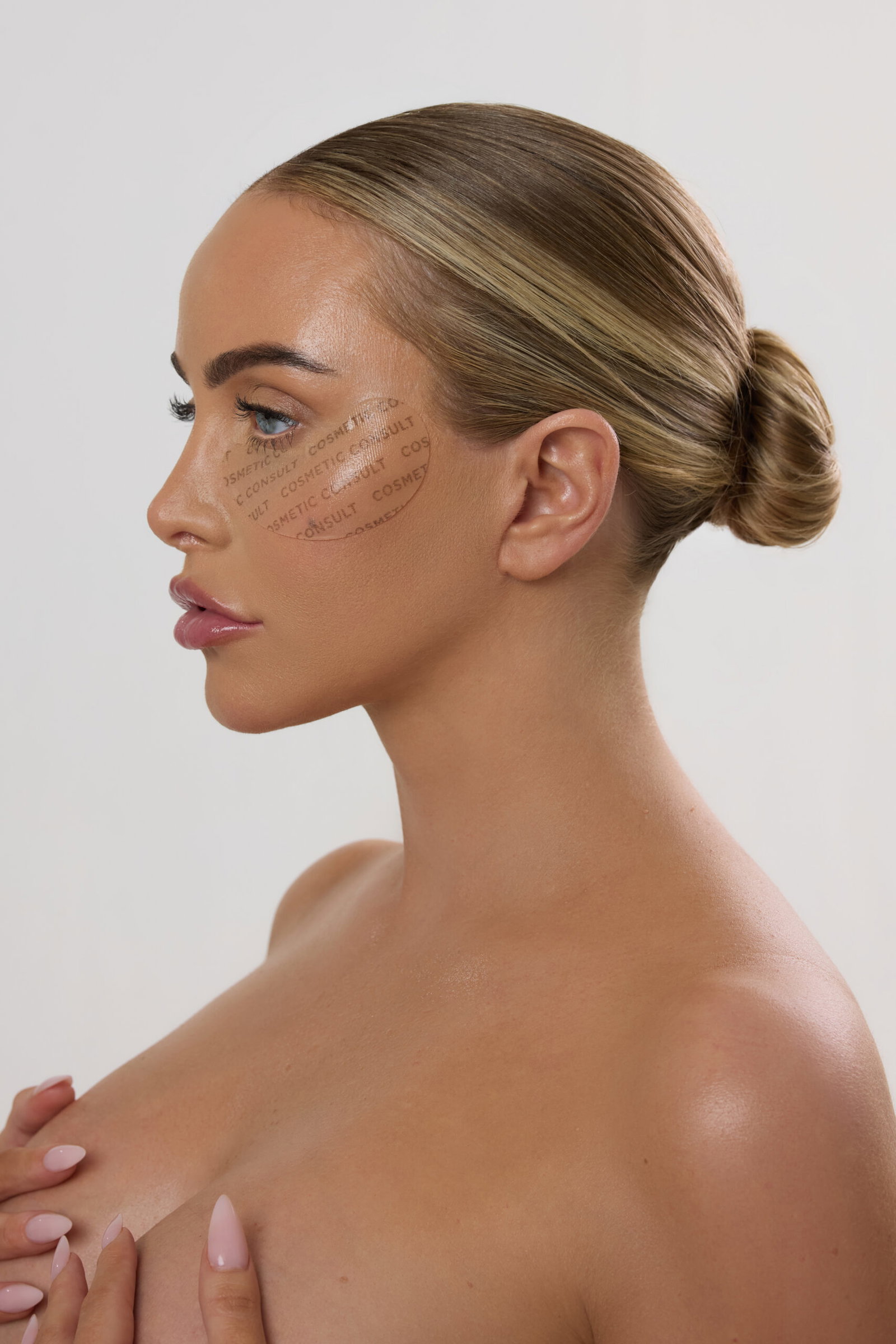 0 527 | Live That Glow Side profile of a woman with a circular under-eye cosmetic patch on her cheek.