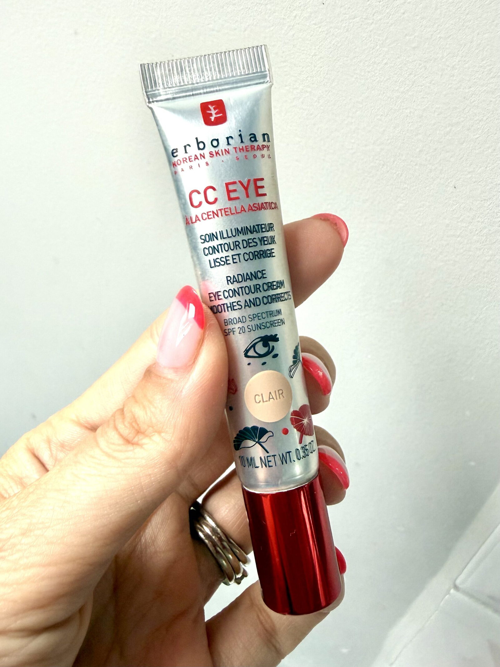 Tube of Erborian CC Eye cream being held by a hand with pink nail polish against a light background. This is an informative image of a skincare product.