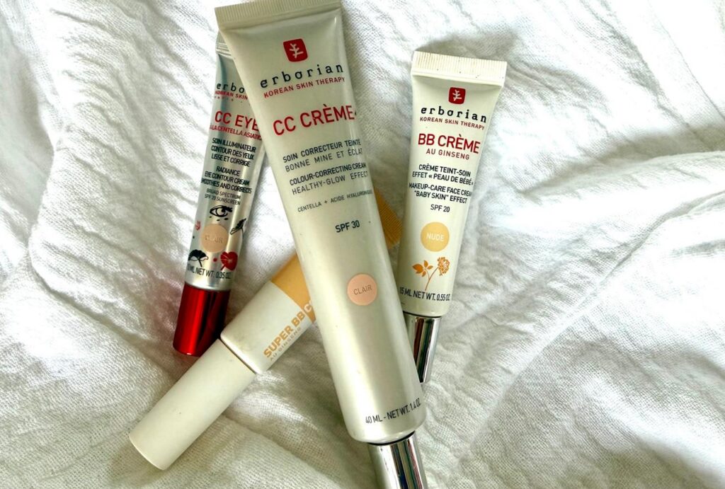 Several Erborian skincare tubes (CC Cream and BB Cream) lying on a white fabric surface on a towel-like cloth.