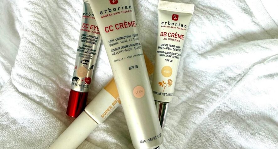 Several Erborian skincare tubes (CC Cream and BB Cream) lying on a white fabric surface on a towel-like cloth.