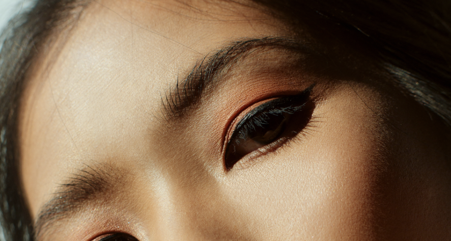 Close-up of a person’s eyes with orange eyeshadow and black eyeliner.