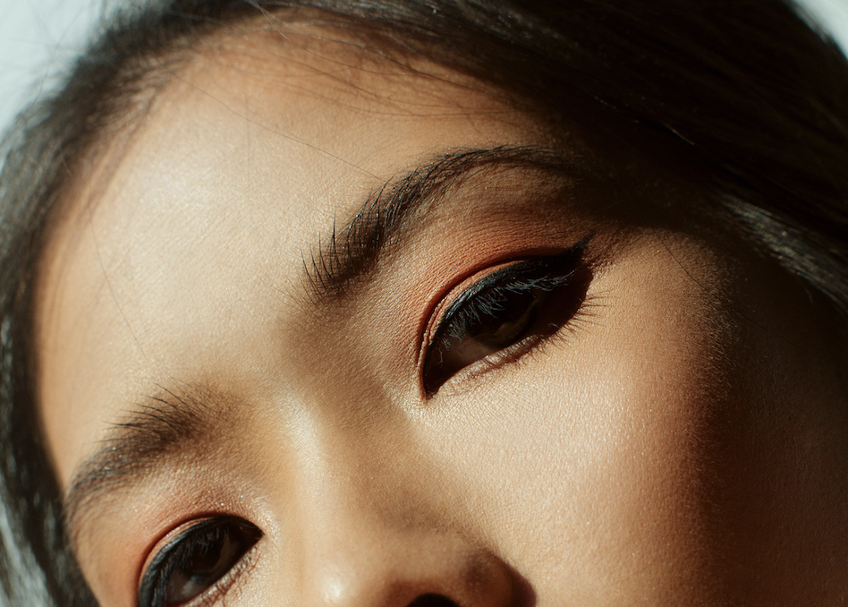 Close-up of a person’s eyes with orange eyeshadow and black eyeliner.