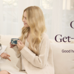 Two women sit on a sofa, converse with mugs in hand during a casual chat at home, warm and friendly vibe.