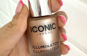 ICONIC London Illuminator in the shade Original held in hand, showing the frosted glass bottle, silver cap and black dropper applicator.