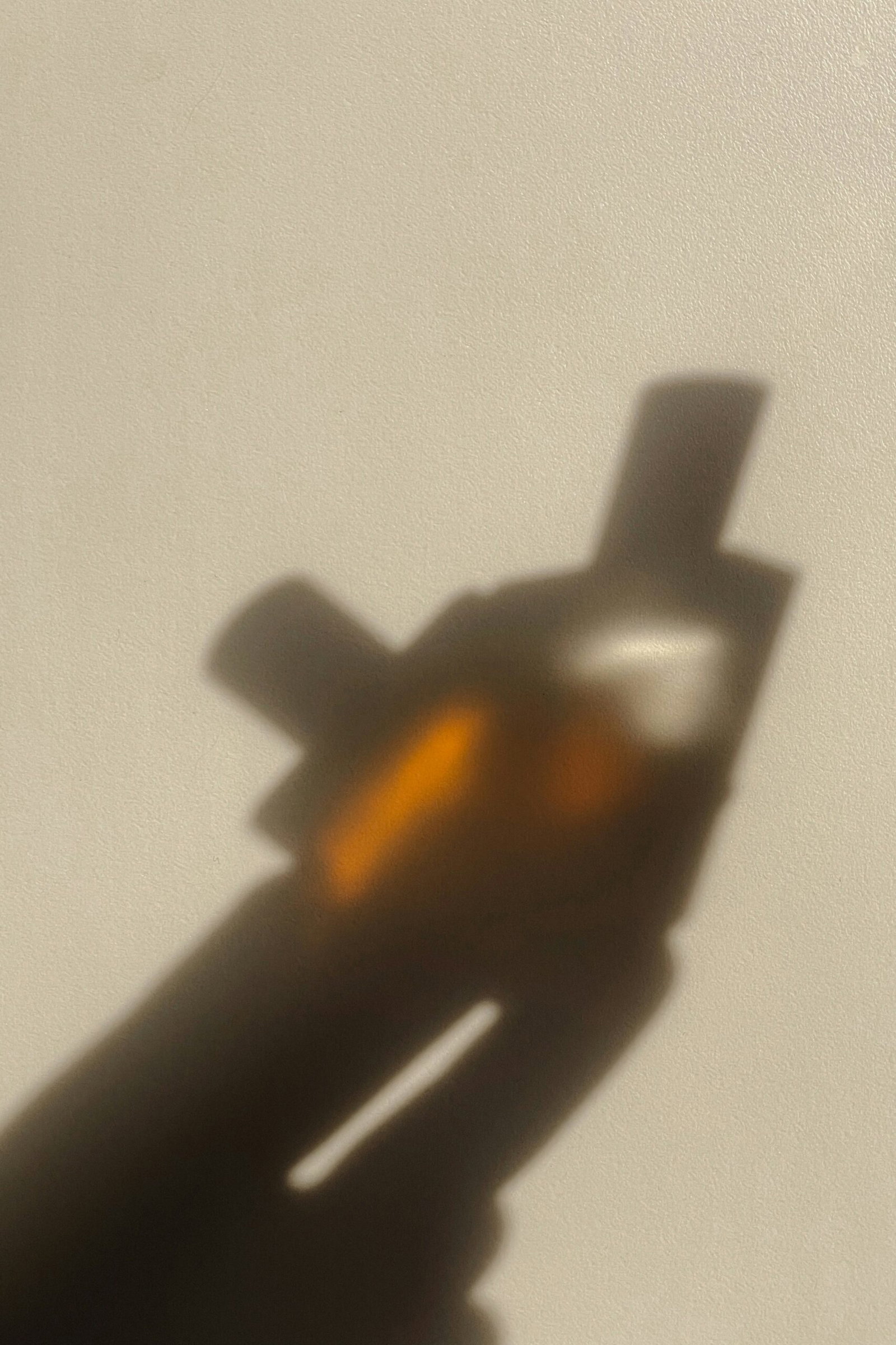 mathilde-langevin-_9532P94wWw-unsplash | Live That Glow Shadow of a hand holding a small rectangular device (likely a smartphone) on a beige wall nearby light.