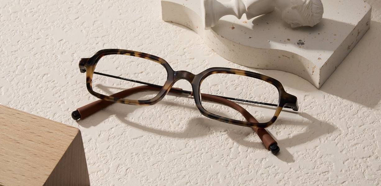 | Live That Glow Rectangular tortoiseshell eyeglasses with brown temples resting on a light textured surface.
