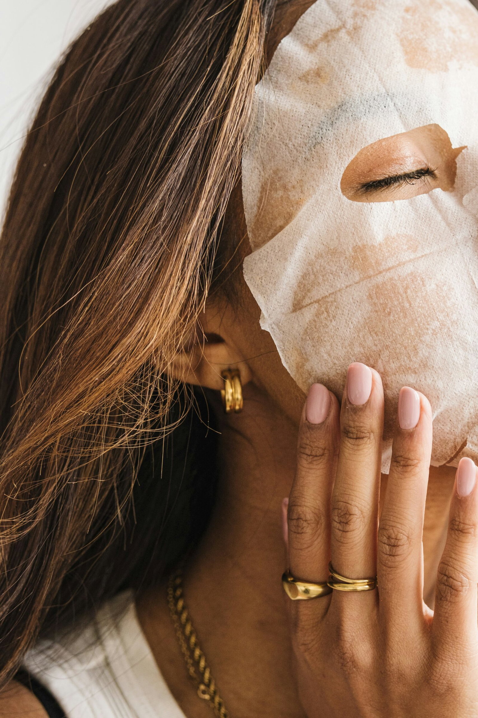 Woman relaxing with a sheet face mask during an at-home spa night