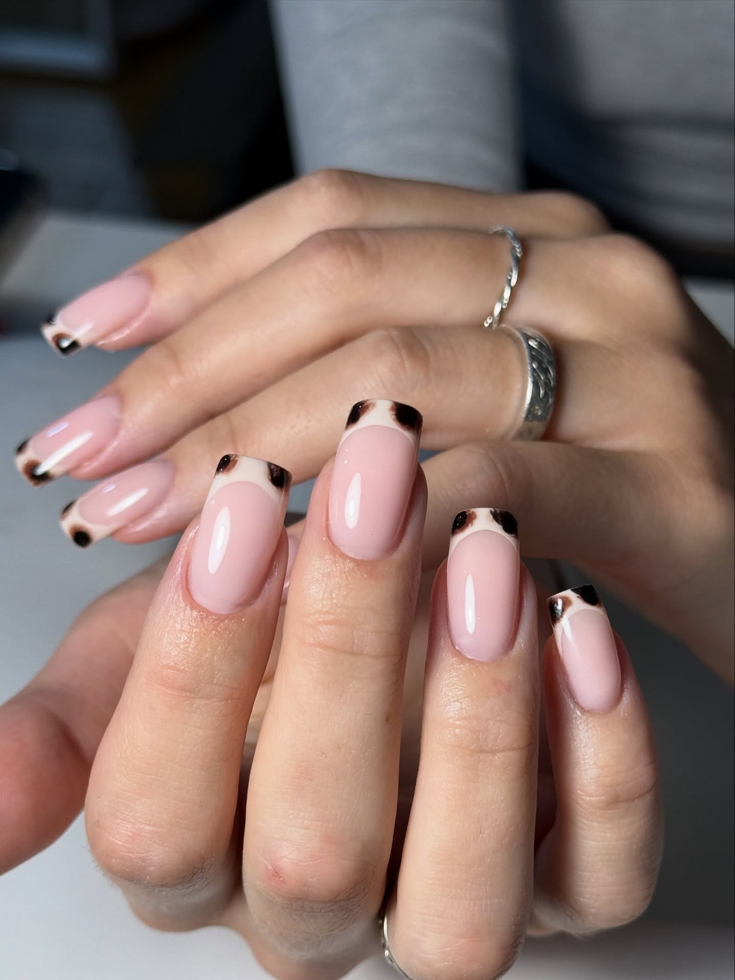 Tortoiseshell French tip nails over a sheer pink base.