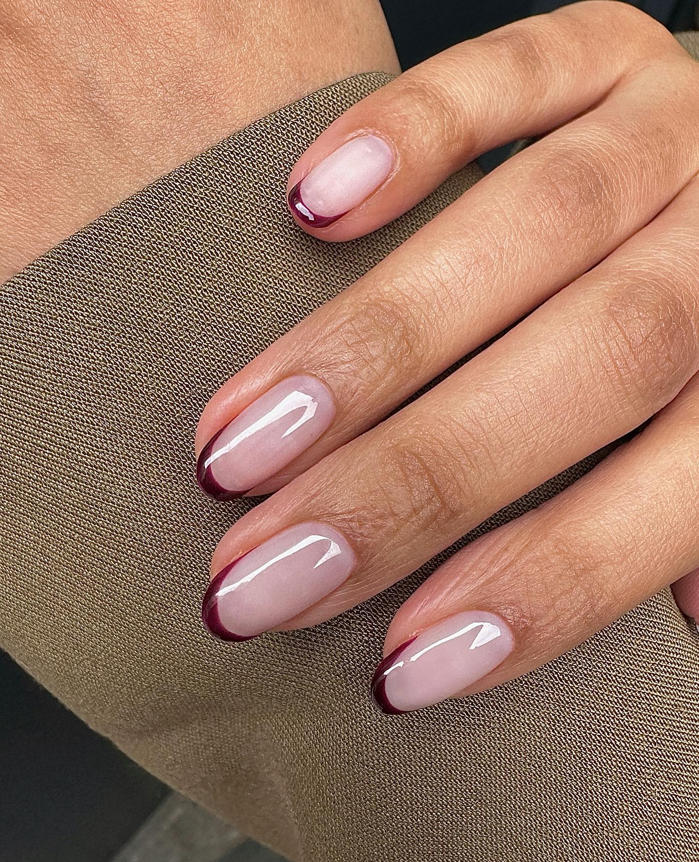 Burgundy French tip nails over a sheer neutral pink base.