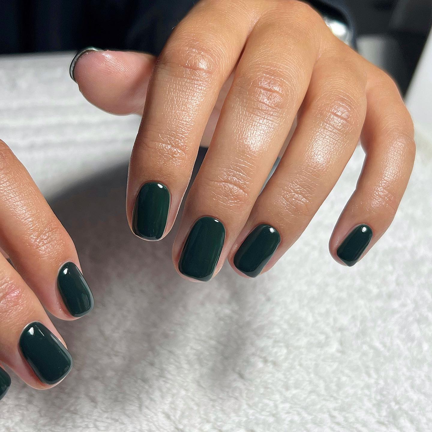 Short dark forest green nails with a glossy finish for autumn.