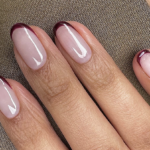 Glossy burgundy French tip nails over a sheer pink base for autumn.