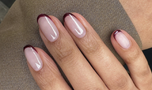 Glossy burgundy French tip nails over a sheer pink base for autumn.