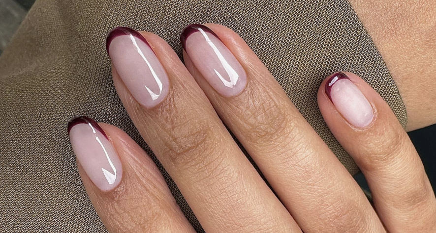 Glossy burgundy French tip nails over a sheer pink base for autumn.