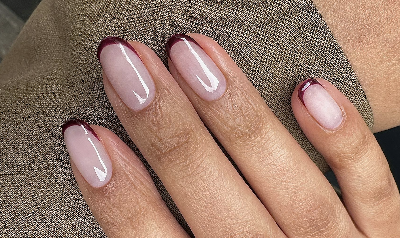 Glossy burgundy French tip nails over a sheer pink base for autumn.