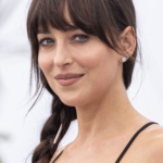 Dakota Johnson with a soft brunette fringe, loose face-framing strands and a low ponytail.