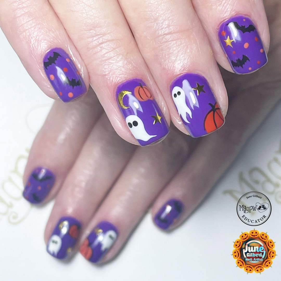 Purple Halloween nails decorated with white ghosts, black bats, orange pumpkins and gold stars