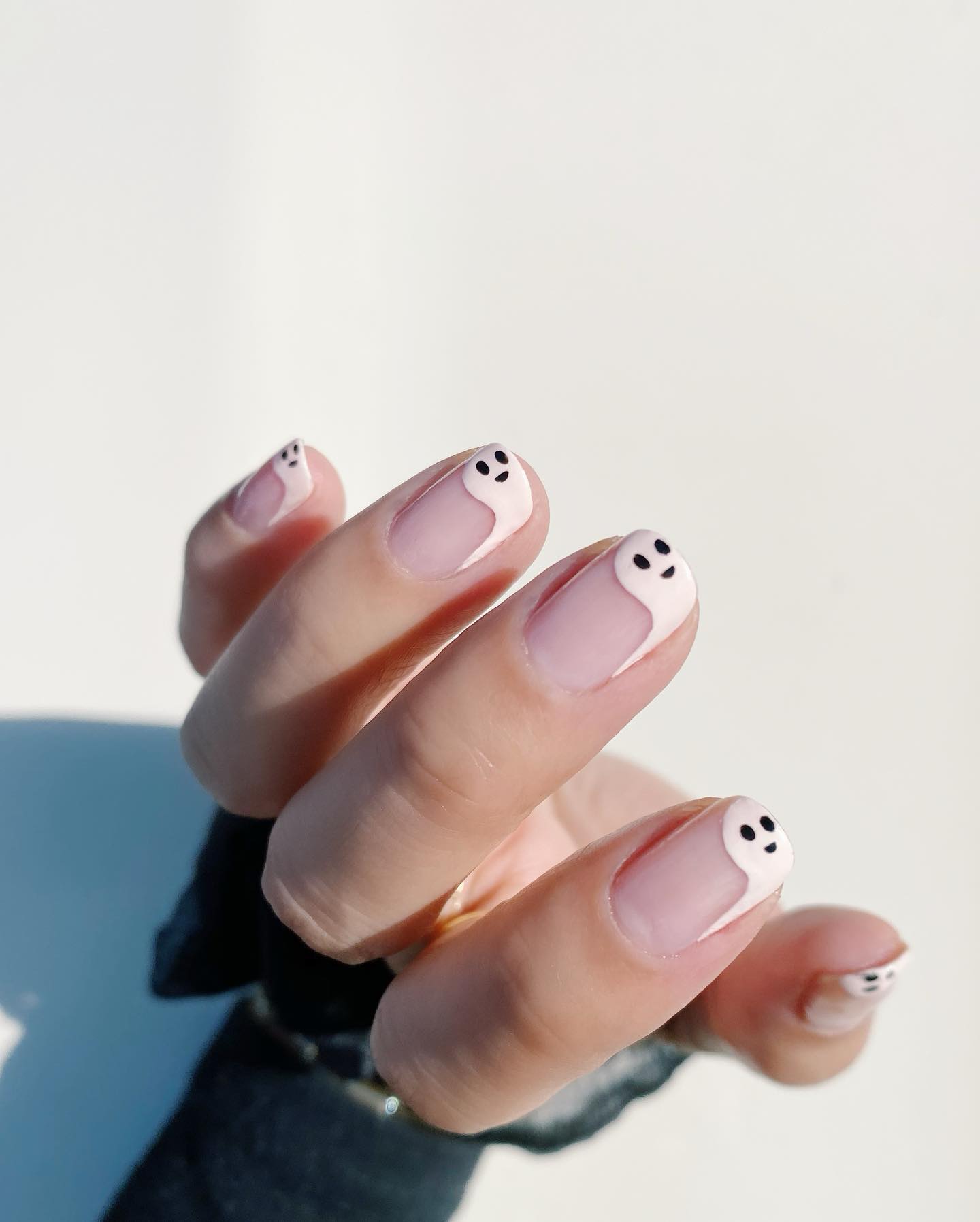 Short nude nails with white ghost-shaped French tips and tiny black faces