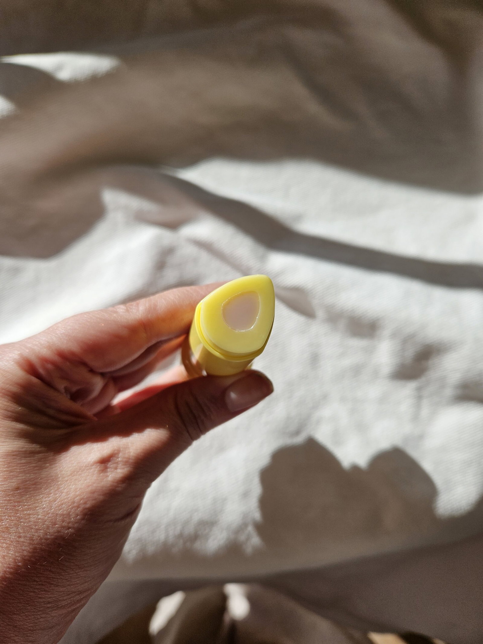 Close-up of the Tage Retinal Multi Balm Stick's triangular applicator, showing its pink Volufiline centre surrounded by a yellow retinal formula.