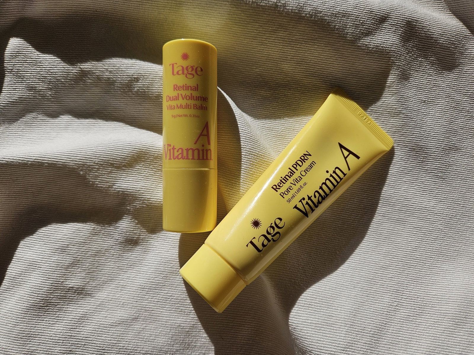 Tage Vita A Retinal Multi Balm Stick and Retinal PDRN Pore Booster Cream in bright yellow packaging, photographed together in natural sunlight.