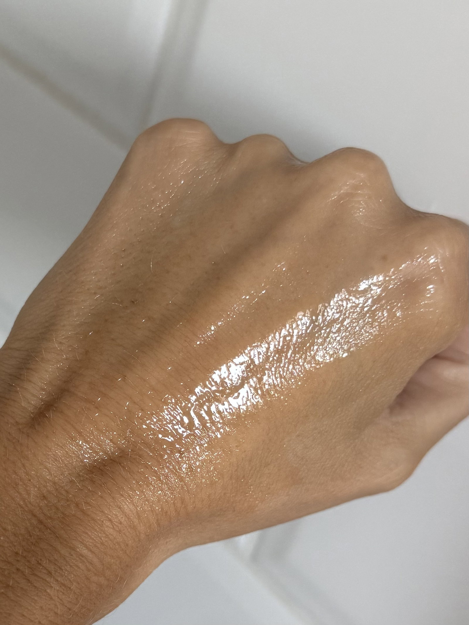 The INKEY List Oat Balm Cleanser spread across the back of a hand, showing its glossy, oil-like texture as it melts into the skin.